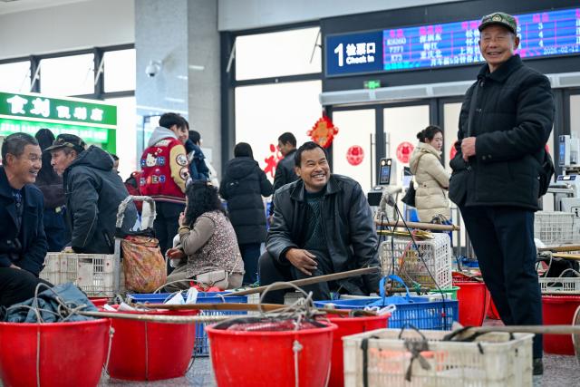 (260213) -- TONGREN, Feb. 13, 2026 (Xinhua) -- Villagers from Hunan Province talk at the Tongren Railway Station in Tongren City, southwest China's Guizhou Province, Feb. 12, 2026.
  The train No. 7272/7271 has run across the mountainous areas in Hunan, Guizhou and Chongqing for almost 20 years. With an average speed of just 40 kilometers per hour, the train has made it easier for residents along the route to travel and commute, while also helping local products reach wider markets. (Photo by Yuan Fuhong/Xinhua)