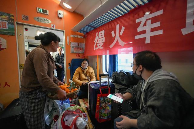 (260213) -- TONGREN, Feb. 13, 2026 (Xinhua) -- A villager (L) from Hunan Province sells fruits to passengers on the train No. 7272 on Feb. 12, 2026.
  The train No. 7272/7271 has run across the mountainous areas in Hunan, Guizhou and Chongqing for almost 20 years. With an average speed of just 40 kilometers per hour, the train has made it easier for residents along the route to travel and commute, while also helping local products reach wider markets. (Photo by Long Jianrui/Xinhua)