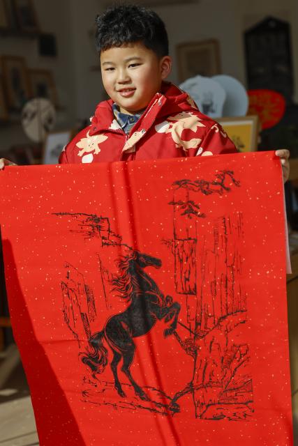 (260213) -- HUANGSHAN, Feb. 13, 2026 (Xinhua) -- A boy shows a woodblock print themed on the Year of the Horse at a studio in Tunxi District of Huangshan City, east China's Anhui Province, Feb. 11, 2026.
  This year's Spring Festival marks the beginning of the Year of the Horse. With the vivid horse designs, the ingeniously crafted Huizhou woodblock print, a provincial-level intangible cultural heritage, adds an enduring charm to the authentic Chinese aesthetics. (Photo by Shi Yalei/Xinhua)