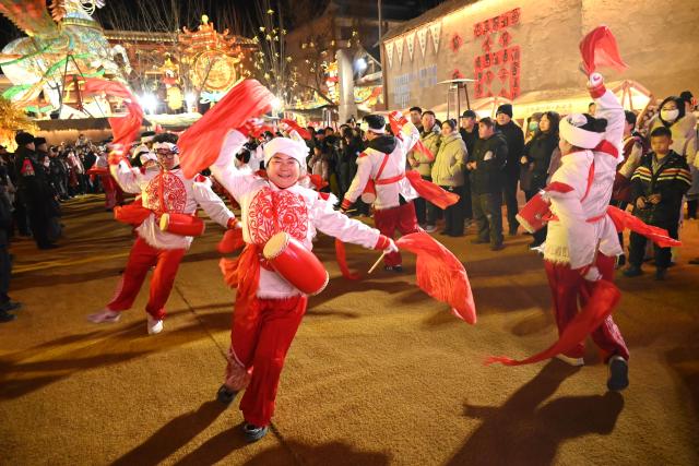 (260213) -- BEIJING, Feb. 13, 2026 (Xinhua) -- Tourists watch waist drum performance at a night market in Dunhuang, northwest China's Gansu Province, Feb. 12, 2026. Various festive events are held across China to celebrate the upcoming Chinese New Year of the Horse. (Photo by Zhang Xiaoliang/Xinhua)