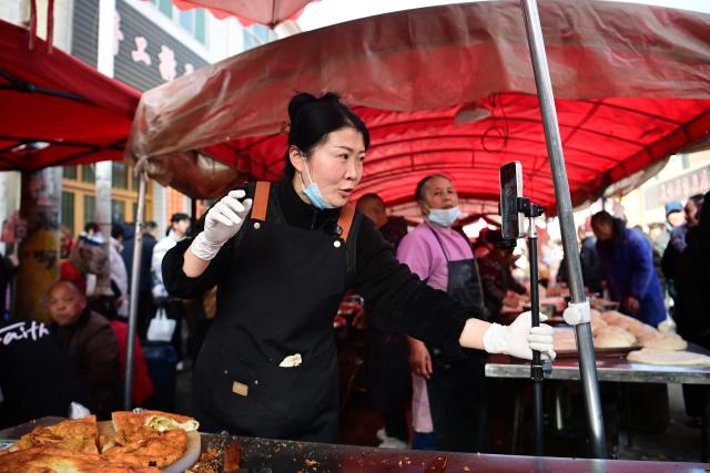 (260213) -- XI'AN, Feb. 13, 2026 (Xinhua) -- A vendor promotes local food via live-streaming at the Jiaodai Market in Jiaodai Town of Lantian County, northwest China's Shaanxi Province, Feb. 13, 2026. The Jiaodai Market, located on a key route over the Qinling Mountains, has been a trading hub for mountain produces since ancient times. 
   As the largest township market in Lantian, Jiaodai Market accommodates more than 1,500 stalls, dealing a variety of goods such as local specialties, daily necessities, farming tools and livestock, and local snacks. It also serves as a major tourist attraction now, thanks to formalized management and effective promotion efforts. (Xinhua/Zou Jingyi)