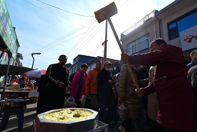 (260213) -- XI'AN, Feb. 13, 2026 (Xinhua) -- People watch a man making glutinous rice cake at the Jiaodai Market in Jiaodai Town of Lantian County, northwest China's Shaanxi Province, Feb. 13, 2026. The Jiaodai Market, located on a key route over the Qinling Mountains, has been a trading hub for mountain produces since ancient times. 
   As the largest township market in Lantian, Jiaodai Market accommodates more than 1,500 stalls, dealing a variety of goods such as local specialties, daily necessities, farming tools and livestock, and local snacks. It also serves as a major tourist attraction now, thanks to formalized management and effective promotion efforts. (Xinhua/Zou Jingyi)