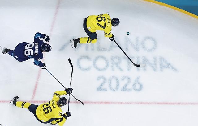 (260213) -- MILAN, Feb. 13, 2026 (Xinhua) -- Rickard Rakell (top) of Sweden breaks through during the ice hockey men's preliminary round group B match between Finland and Sweden at the Milan-Cortina 2026 Olympic Winter Games in Milan, Italy, Feb. 13, 2026. (Xinhua/Tao Xiyi)