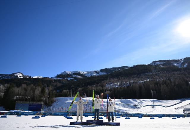(260213) -- TESERO, Feb. 13, 2026 (Xinhua) -- Gold medalist Johannes Hoesflot Klaebo (C) of Norway, silver medalist Mathis Desloges (L) of France and bronze medalist Einar Hedegart of Norway pose for photos during the awarding ceremony for the Cross-Country Skiing Men's 10km Interval Start Free at the Milano Cortina 2026 Olympic Winter Games in Tesero, Italy, Feb. 13, 2026. (Xinhua/He Canling)