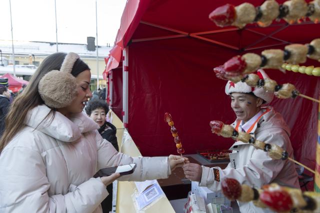 (260213) -- HELSINKI, Feb. 13, 2026 (Xinhua) -- A participant buys Chinese traditional snack at a food stall during the 2026 "Happy Chinese New Year" folk fair in Helsinki, Finland, Feb. 13, 2026. (Photo by Matti Matikainen/Xinhua)