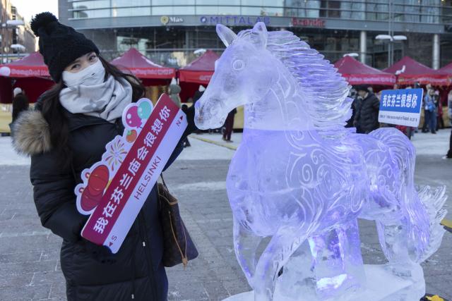 (260213) -- HELSINKI, Feb. 13, 2026 (Xinhua) -- A participant poses for a photo with a Year of the Horse-themed ice sculpture at the 2026 "Happy Chinese New Year" folk fair in Helsinki, Finland, Feb. 13, 2026. (Photo by Matti Matikainen/Xinhua)