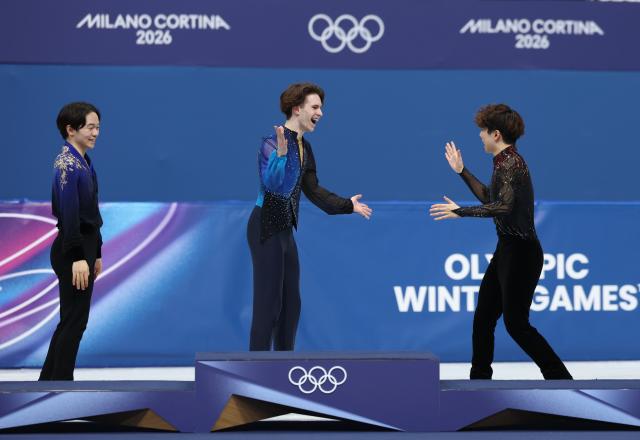 (260214) -- MILAN, Feb. 14, 2026 (Xinhua) -- Gold medalist Mikhail Shaidorov (C) of Kazakhstan reacts with bronze medalist Sato Shun (R) of Japan during the awarding ceremony for the men's single skating free skating of figure skating event at the Milan-Cortina 2026 Olympic Winter Games in Milan, Italy, Feb. 13, 2026. (Xinhua/Li Ming)