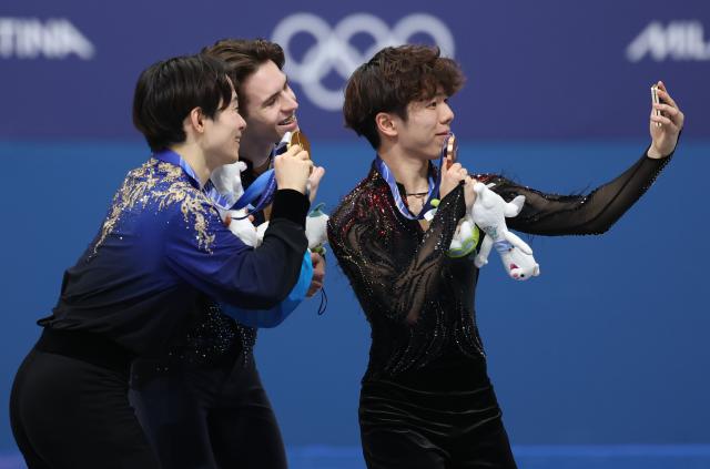 (260214) -- MILAN, Feb. 14, 2026 (Xinhua) -- Silver medalist Kagiyama Yuma of Japan, gold medalist Mikhail Shaidorov of Kazakhstan and bronze medalist Sato Shun of Japan (L to R) take selfies on the podium after the men's single skating free skating of figure skating event at the Milan-Cortina 2026 Olympic Winter Games in Milan, Italy, Feb. 13, 2026. (Xinhua/Li Ming)