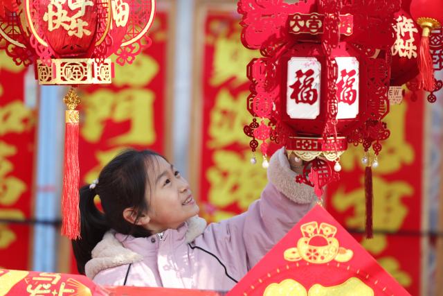 (260214) -- BEIJING, Feb. 14, 2026 (Xinhua) -- A girl selects Chinese New Year decorations at a market in Tancheng County of Linyi City, east China's Shandong Province, Feb. 13, 2026.
  Markets across the country are bustling nowadays as people flock there to stock up on goods in preparation for the upcoming Spring Festival, or the Chinese New Year. (Photo by Zhang Chunlei/Xinhua)