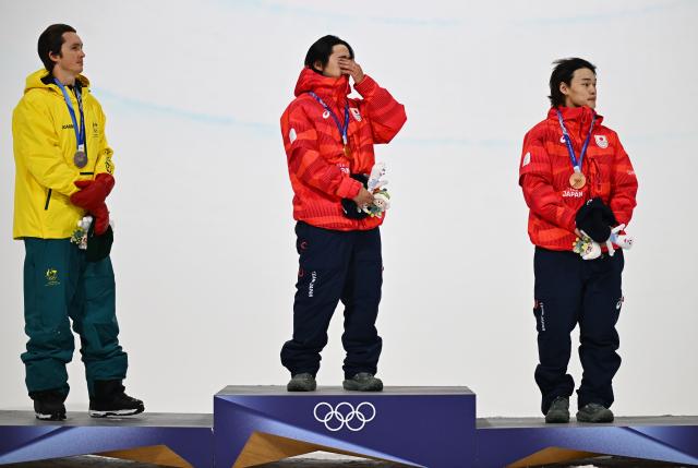 (260214) -- LIVIGNO, Feb. 14, 2026 (Xinhua) -- Gold medalist Totsuka Yuto (C) of Japan, silver medalist Scotty James (L) of Australia and bronze medalist Yamada Ryusei of Japan react during the awarding ceremony of the men's snowboard halfpipe at the Milan-Cortina 2026 Olympic Winter Games in Livigno, Italy, Feb. 13, 2026. (Xinhua/Zhang Hongxiang)