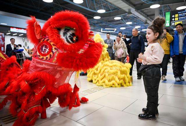 (260214) -- ALMATY, Feb. 14, 2026 (Xinhua) -- Lion dance performers interact with a Kazakh child during a Chinese New Year cultural event at the Almaty International Airport in Almaty, Kazakhstan, Feb. 13, 2026. (Xinhua/Li Renzi)
