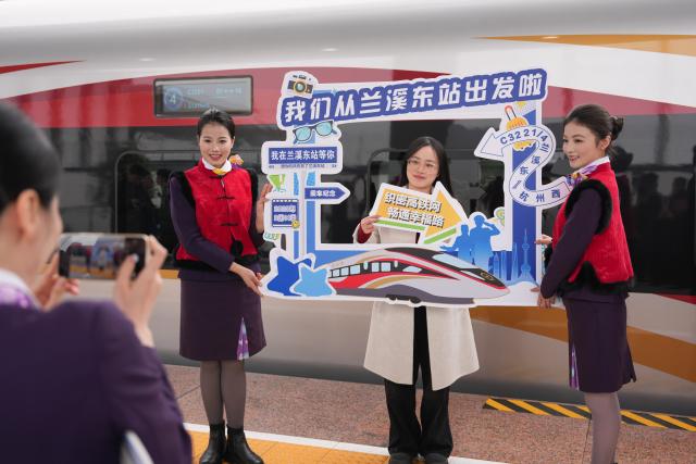 (260214) -- LANXI, Feb. 14, 2026 (Xinhua) -- A passenger poses for a photo with train conductors at the platform of Lanxi East Railway Station in Lanxi, east China's Zhejiang Province, Feb. 14, 2026. The Lanxi-Jiande section of a 64.51-kilometer high-speed railway linking cities of Jinhua and Jiande, both in east China's Zhejiang, was officially put into operation on Saturday. (Xinhua/Huang Zongzhi)