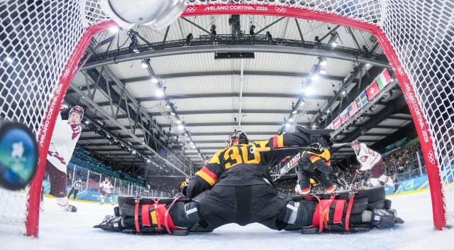 (260214) -- MILAN, Feb. 14, 2026 (Xinhua) -- Dans Locmelis (1st L) of Latvia scores during the ice hockey men's preliminary round group C match between Germany and Latvia of the Milan-Cortina 2026 Olympic Winter Games in Milan, Italy, Feb. 14, 2026. (Sun Fei/Pool via Xinhua)