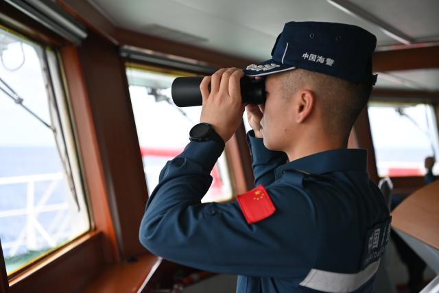 (260214) -- SOUTH CHINA SEA, Feb. 14, 2026 (Xinhua) -- Law enforcer Wang Hong watches out during a patrol mission aboard the China Coast Guard (CCG) vessel Wanshan in the territorial waters of China's Huangyan Dao, Feb. 6, 2026. Right ahead of the Chinese New Year, a traditional occasion for family reunion in China, a group of young law enforcers remain loyally stationed and highly alert around the clock, hundreds of miles away from their loved ones. (Photo by Zhai Yifan/Xinhua)