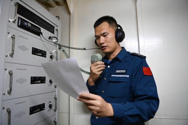 (260214) -- SOUTH CHINA SEA, Feb. 14, 2026 (Xinhua) -- Law enforcer Chen Chen performs the daily broadcast aboard the China Coast Guard (CCG) vessel Wanshan in the territorial waters of China's Huangyan Dao, Feb. 10, 2026. Right ahead of the Chinese New Year, a traditional occasion for family reunion in China, a group of young law enforcers remain loyally stationed and highly alert around the clock, hundreds of miles away from their loved ones. (Photo by Zhai Yifan/Xinhua)