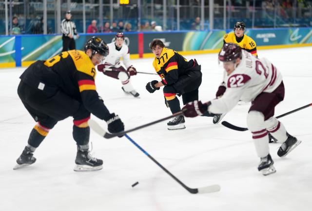 (260214) -- MILAN, Feb. 14, 2026 (Xinhua) -- John Peterka (C) of Germany loses his helmet during the ice hockey men's preliminary round group C match between Germany and Latvia of the Milan-Cortina 2026 Olympic Winter Games in Milan, Italy, Feb. 14, 2026. (Xinhua/Sun Fei)