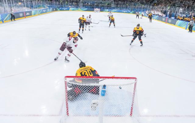 (260214) -- MILAN, Feb. 14, 2026 (Xinhua) -- Eduards Tralmaks (1st L) of Latvia shoots to score during the ice hockey men's preliminary round group C match between Germany and Latvia of the Milan-Cortina 2026 Olympic Winter Games in Milan, Italy, Feb. 14, 2026. (Xinhua/Sun Fei)