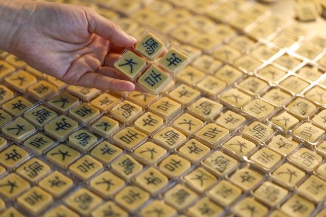 (260214) -- HEFEI, Feb. 14, 2026 (Xinhua) -- A staff member displays character-inlaid candies cubes in Qimen County of Huangshan City, east China's Anhui Province, Jan. 13, 2026.
  As the Spring Festival approaches, inheritors of the making crafts of character-inlaid candy, an intangible cultural heritage in Qimen County, are getting busy as this specialty sweet is highly sought for during the festival. 
   The making process of the candy includes boiling sugar, grinding powder, stirring, compacting, making inlaid characters, stretching sugar bar and slicing. Because the character embedded in the center of the candy always carries auspicious meanings, such candy is very popular during festivals.
   Candies inlaid with Chinese character "Ma," referring to the horse, are the most popular now, as this Spring Festival will usher in the Year of the Horse. (Photo by Shi Yalei/Xinhua)