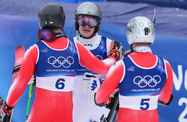 (260214) -- BORMIO, Feb. 14, 2026 (Xinhua) -- Silver medalist Marco Odermatt (R) of Switzerland and bronze medalist Loic Meillard (L) of Switzerland react with gold medalist Lucas Pinheiro Braathen of Brazil after the alpine skiing men's giant slalom run 2 at the Milan-Cortina 2026 Olympic Winter Games in Bormio, Italy, Feb. 14, 2026. (Xinhua/Hu Huhu)