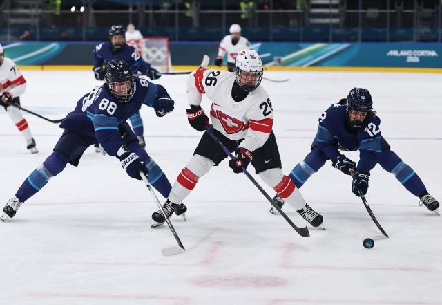 (260215) -- MILAN, Feb. 15, 2026 (Xinhua) -- Naemi Herzig (C) of Switzerland vies with Ronja Savolainen (L) and Sanni Vanhanen of Finland during the ice hockey women's play-offs quarterfinal between Finland and Switzerland at the Milan-Cortina 2026 Olympic Winter Games in Milan, Italy, Feb. 14, 2026. (Xinhua/Wang Kaiyan)
