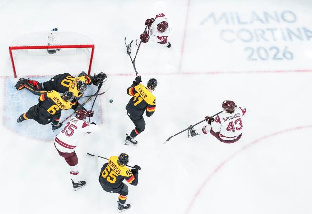 (260215) -- MILAN, Feb. 15, 2026 (Xinhua) -- Martins Dzierkals (top) of Latvia competes during the ice hockey men's preliminary round group C match between Germany and Latvia of the Milan-Cortina 2026 Olympic Winter Games in Milan, Italy, Feb. 14, 2026. (Xinhua/Sun Fei)