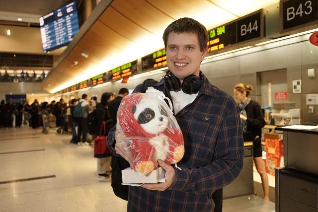 (260215) -- LOS ANGELES, Feb. 15, 2026 (Xinhua) -- A tourist poses for a photo while holding a gift presented by Air China at Los Angeles International Airport in Los Angeles, California, the United States, on Feb. 13, 2026. TO GO WITH: "American tourists embark on China trips to experience Spring Festival" (Photo by Zeng Hui/Xinhua)