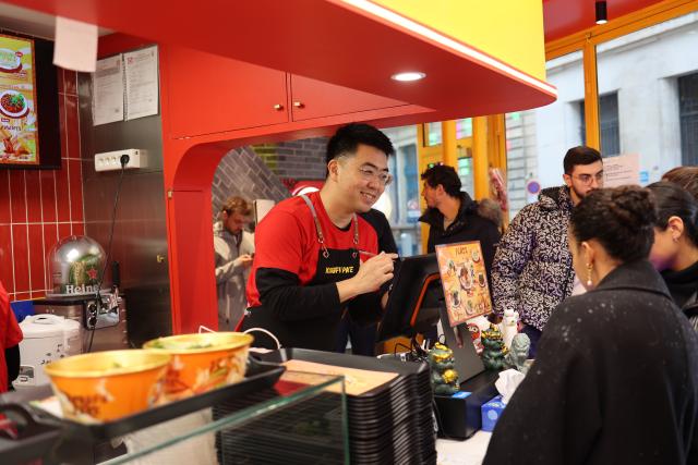(260215) -- TAIYUAN, Feb. 15, 2026 (Xinhua) -- This undated file photo shows Guo Zhanglong helping a customer order dishes at his knife-sliced noodles restaurant in Paris, France. TO GO WITH "China Focus: Slurping a taste of timeless flavors and history in every strand of Chinese noodles" (Xinhua)
