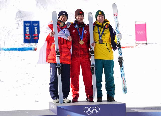 (260215) -- LIVIGNO, Feb. 15, 2026 (Xinhua) -- Gold medalist Mikael Kingsbury (C) of Canada, silver medalist Horishima Ikuma (L) of Japan and bronze medalist Matt Graham of Australia pose for photos during the awarding ceremony for the freestyle skiing men's dual moguls at the Milan-Cortina 2026 Olympic Winter Games in Livigno, Italy, Feb. 15, 2026. (Xinhua/Wu Huiwo)