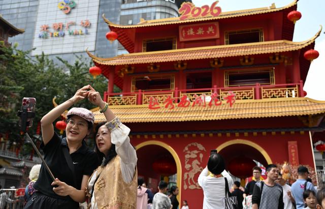 (260215) -- GUANGZHOU, Feb. 15, 2026 (Xinhua) -- People pose for a selfie at a flower market in Yuexiu District, Guangzhou, south China's Guangdong Province, Feb. 15, 2026. China is alive with vibrant celebrations with the Spring Festival just around the corner. (Xinhua/Deng Hua)