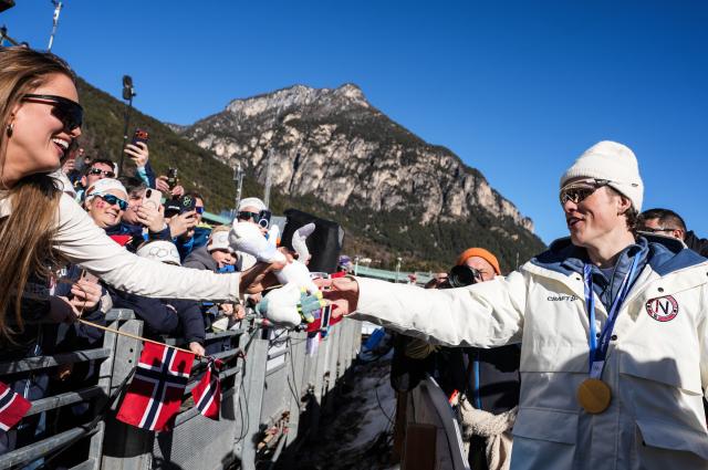 (260215) -- TESERO, Feb. 15, 2026 (Xinhua) -- Johannes Hoesflot Klaebo (R) of Norway gives the mascot to a supporter after the awarding ceremony for the cross-country skiing men's 4X7.5km relay match at the Milan-Cortina 2026 Olympic Winter Games in Tesero, Italy, Feb. 15, 2026. (Xinhua/Peng Ziyang)