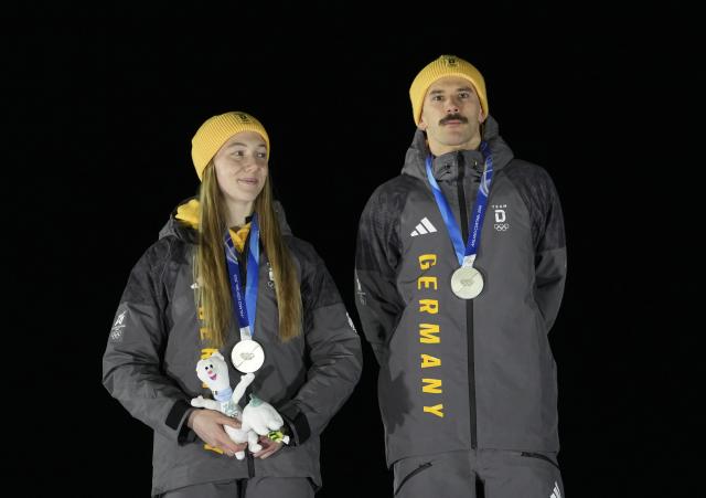 (260215) -- CORTINA D'AMPEZZO, Feb. 15, 2026 (Xinhua) -- Silver medalists Susanne Kreher (L)/Axel Jungk of Germany pose for photos during the awarding ceremony of the skeleton mixed team competition at the Milan-Cortina 2026 Olympic Winter Games in Cortina, Italy, Feb. 15, 2026. (Xinhua/Li Gang)