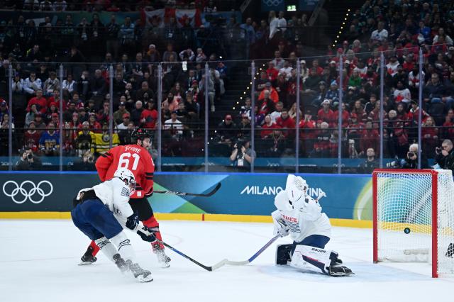 (260216) -- MILAN, Feb. 16, 2026 (Xinhua) -- Mark Stone (top) of Canada scores during the ice hockey men's preliminary round group A match between Canada and France at the Milan-Cortina 2026 Olympic Winter Games in Milan, Italy, Feb. 15, 2026. (Xinhua/Zhang Haofu)