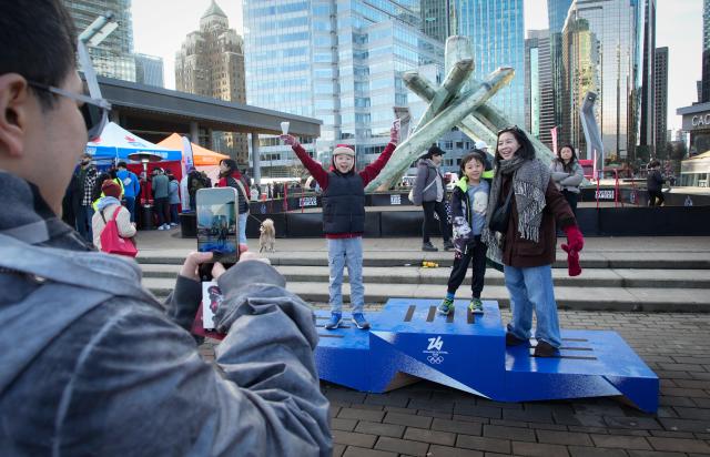 (260216) -- VANCOUVER, Feb. 16, 2026 (Xinhua) -- People pose for photos at the 2026 Milan-Cortina Winter Olympics podium during the Team Canada Fanfest in Vancouver, Canada, on Feb. 15, 2026. The event is part of a nationwide FanFest series planned for Canadian cities during 2026 Milan-Cortina Winter Olympics. (Photo by Liang Sen/Xinhua)