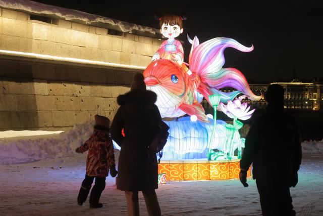 (260216) -- ST. PETERSBURG, Feb. 16, 2026 (Xinhua) -- People view a light installation in St. Petersburg, Russia, Feb. 15, 2026.
  Ten sets of large-scale lanterns and light installations made in Zigong of southwest China's Sichuan Province lit up along the Neva River here on Sunday to celebrate upcoming the Chinese New Year. (Photo by Irina Motina/Xinhua)