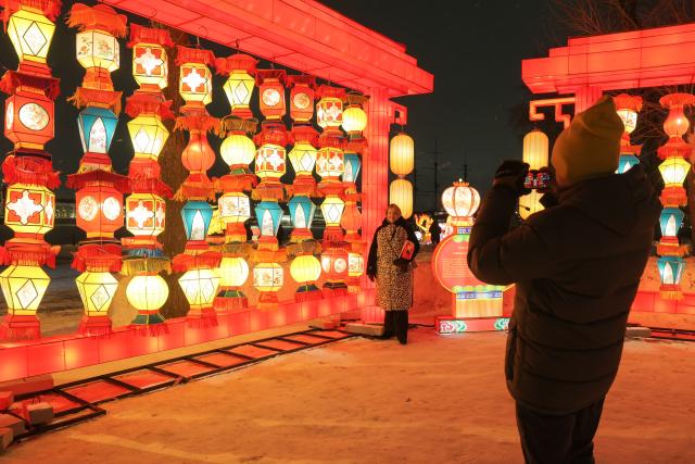 (260216) -- ST. PETERSBURG, Feb. 16, 2026 (Xinhua) -- A tourist takes photos of lanterns in St. Petersburg, Russia, Feb. 15, 2026.
  Ten sets of large-scale lanterns and light installations made in Zigong of southwest China's Sichuan Province lit up along the Neva River here on Sunday to celebrate upcoming the Chinese New Year. (Photo by Irina Motina/Xinhua)