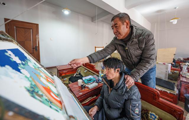 (260216) -- LHASA, Feb. 16, 2026 (Xinhua) -- Norbu Sidar instructs an apprentice at the Xizang Academy of Thangka in Lhasa, southwest China's Xizang Autonomous Region, Feb. 10, 2026. On the afternoon of Feb. 10, sunlight streamed through the windows of the Xizang Academy of Thangka, illuminating an unfinished thangka painting. Norbu Sidar stood beside a young apprentice. He reached out, gently placing his finger on a specific spot on the canvas, and quietly guided the apprentice on the direction of the lines. 
   Thangka, renowned for its meticulous composition, vibrant colors, and profound cultural connotations, was listed among the first batch of China's national intangible cultural heritages in 2006. Recording Tibetan history, culture, medicine, astronomy, and other knowledge, it carries the spiritual beliefs and aesthetic wisdom of people in Xizang throughout the times.
   Norbu Sidar is a national-level inheritor of the Tibetan thangka. As a child, he learned thangka painting techniques from his grandfather. He recalled, "Time was most precious when I was little. I could only learn to paint thangka in my spare time after helping the family with farm and livestock work." From 2005 to 2015, he spent ten years as a restoration expert undertaking the mural restoration project at the Potala Palace. In 2016, he donated the 18 thangka works he had copied at the Potala Palace over the decade to the Palace. "These ten years have been the most meaningful part of my life," he recalled.
   In 1992, Norbu Sidar began taking on students. Ten years later, he led the founding of the Xizang Academy of Thangka. Today, as a master's supervisor at the School of Arts of Xizang University, he guides graduate students in studying the history of thangka and encourages young people to experiment with new forms of expression. To date, over 400 students are, like him, contributing to the development of Tibetan thangka art.
    After being elected as a member of the National Committee of the Chinese People's Political Consultative Conference, Norbu Sidar felt he had the responsibility to do more to make thangka, the artistic treasure in Xizang, recognized, supported and passed down through generations. (Xinhua/Tenzin Nyida)
