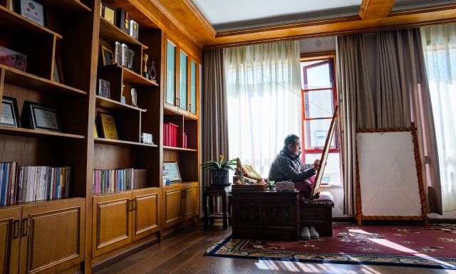 (260216) -- LHASA, Feb. 16, 2026 (Xinhua) -- Norbu Sidar draws the pattern of a thangka at his office at the Xizang Academy of Thangka in Lhasa, southwest China's Xizang Autonomous Region, Feb. 10, 2026. On the afternoon of Feb. 10, sunlight streamed through the windows of the Xizang Academy of Thangka, illuminating an unfinished thangka painting. Norbu Sidar stood beside a young apprentice. He reached out, gently placing his finger on a specific spot on the canvas, and quietly guided the apprentice on the direction of the lines. 
   Thangka, renowned for its meticulous composition, vibrant colors, and profound cultural connotations, was listed among the first batch of China's national intangible cultural heritages in 2006. Recording Tibetan history, culture, medicine, astronomy, and other knowledge, it carries the spiritual beliefs and aesthetic wisdom of people in Xizang throughout the times.
   Norbu Sidar is a national-level inheritor of the Tibetan thangka. As a child, he learned thangka painting techniques from his grandfather. He recalled, "Time was most precious when I was little. I could only learn to paint thangka in my spare time after helping the family with farm and livestock work." From 2005 to 2015, he spent ten years as a restoration expert undertaking the mural restoration project at the Potala Palace. In 2016, he donated the 18 thangka works he had copied at the Potala Palace over the decade to the Palace. "These ten years have been the most meaningful part of my life," he recalled.
   In 1992, Norbu Sidar began taking on students. Ten years later, he led the founding of the Xizang Academy of Thangka. Today, as a master's supervisor at the School of Arts of Xizang University, he guides graduate students in studying the history of thangka and encourages young people to experiment with new forms of expression. To date, over 400 students are, like him, contributing to the development of Tibetan thangka art.
    After being elected as a member of the National Committee of the Chinese People's Political Consultative Conference, Norbu Sidar felt he had the responsibility to do more to make thangka, the artistic treasure in Xizang, recognized, supported and passed down through generations. (Xinhua/Tenzin Nyida)
