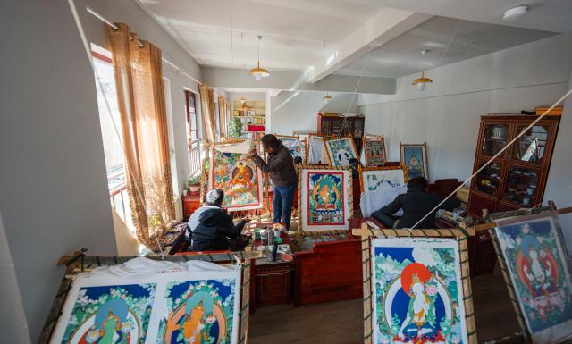 (260216) -- LHASA, Feb. 16, 2026 (Xinhua) -- Norbu Sidar checks the details of a piece of his apprentice's thangka work at the Xizang Academy of Thangka in Lhasa, southwest China's Xizang Autonomous Region, Feb. 10, 2026. On the afternoon of Feb. 10, sunlight streamed through the windows of the Xizang Academy of Thangka, illuminating an unfinished thangka painting. Norbu Sidar stood beside a young apprentice. He reached out, gently placing his finger on a specific spot on the canvas, and quietly guided the apprentice on the direction of the lines. 
   Thangka, renowned for its meticulous composition, vibrant colors, and profound cultural connotations, was listed among the first batch of China's national intangible cultural heritages in 2006. Recording Tibetan history, culture, medicine, astronomy, and other knowledge, it carries the spiritual beliefs and aesthetic wisdom of people in Xizang throughout the times.
   Norbu Sidar is a national-level inheritor of the Tibetan thangka. As a child, he learned thangka painting techniques from his grandfather. He recalled, "Time was most precious when I was little. I could only learn to paint thangka in my spare time after helping the family with farm and livestock work." From 2005 to 2015, he spent ten years as a restoration expert undertaking the mural restoration project at the Potala Palace. In 2016, he donated the 18 thangka works he had copied at the Potala Palace over the decade to the Palace. "These ten years have been the most meaningful part of my life," he recalled.
   In 1992, Norbu Sidar began taking on students. Ten years later, he led the founding of the Xizang Academy of Thangka. Today, as a master's supervisor at the School of Arts of Xizang University, he guides graduate students in studying the history of thangka and encourages young people to experiment with new forms of expression. To date, over 400 students are, like him, contributing to the development of Tibetan thangka art.
    After being elected as a member of the National Committee of the Chinese People's Political Consultative Conference, Norbu Sidar felt he had the responsibility to do more to make thangka, the artistic treasure in Xizang, recognized, supported and passed down through generations. (Xinhua/Tenzin Nyida)