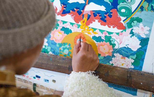 (260216) -- LHASA, Feb. 16, 2026 (Xinhua) -- An apprentice of Norbu Sidar draws a thangka at the Xizang Academy of Thangka in Lhasa, southwest China's Xizang Autonomous Region, Feb. 10, 2026. On the afternoon of Feb. 10, sunlight streamed through the windows of the Xizang Academy of Thangka, illuminating an unfinished thangka painting. Norbu Sidar stood beside a young apprentice. He reached out, gently placing his finger on a specific spot on the canvas, and quietly guided the apprentice on the direction of the lines. 
   Thangka, renowned for its meticulous composition, vibrant colors, and profound cultural connotations, was listed among the first batch of China's national intangible cultural heritages in 2006. Recording Tibetan history, culture, medicine, astronomy, and other knowledge, it carries the spiritual beliefs and aesthetic wisdom of people in Xizang throughout the times.
   Norbu Sidar is a national-level inheritor of the Tibetan thangka. As a child, he learned thangka painting techniques from his grandfather. He recalled, "Time was most precious when I was little. I could only learn to paint thangka in my spare time after helping the family with farm and livestock work." From 2005 to 2015, he spent ten years as a restoration expert undertaking the mural restoration project at the Potala Palace. In 2016, he donated the 18 thangka works he had copied at the Potala Palace over the decade to the Palace. "These ten years have been the most meaningful part of my life," he recalled.
   In 1992, Norbu Sidar began taking on students. Ten years later, he led the founding of the Xizang Academy of Thangka. Today, as a master's supervisor at the School of Arts of Xizang University, he guides graduate students in studying the history of thangka and encourages young people to experiment with new forms of expression. To date, over 400 students are, like him, contributing to the development of Tibetan thangka art.
    After being elected as a member of the National Committee of the Chinese People's Political Consultative Conference, Norbu Sidar felt he had the responsibility to do more to make thangka, the artistic treasure in Xizang, recognized, supported and passed down through generations. (Xinhua/Tenzin Nyida)