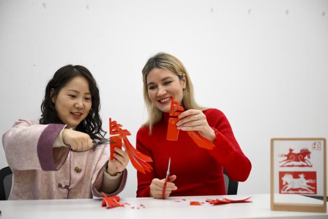 (260216) -- SHANGHAI, Feb. 16, 2026 (Xinhua) -- Aleksandra Antonenko (R) tries her hands with paper-cutting in Shanghai, east China, Feb. 6, 2026.
  Aleksandra Antonenko moved from Russia to pursue her doctorate at Shanghai Jiao Tong University in 2022. She also began to show the charm of everyday life in China to the world with short video clips. 
  In the same year, she met Zhao Yiwei, now her husband, at a coffee shop. Zhao always encourages and supports her diligence, be it in academic pursue or in vlog production.
  With the Spring Festival around the corner, Aleksandra loves wandering through streets and picking out New Year goods. Back to her home, she adds her own tradition to the celebration by cooking Russian dishes for the holiday, turning the table into a blend of two cultures. 
  "The Spring Festival has deep cultural roots," Aleksandra said. "It's a time to bring family together and feel closer."
  Looking ahead, she plans to keep working toward her doctoral degree while continuing to document her life in China through videos. "Every day here brings something new," she said. "I'm excited to share real stories about China with the world."
  From a newbie international student to a Chinese daughter-in-law and a builder of cultural connections, Aleksandra's story reflects a simple belief: love knows no borders. (Xinhua/Chen Haoming)