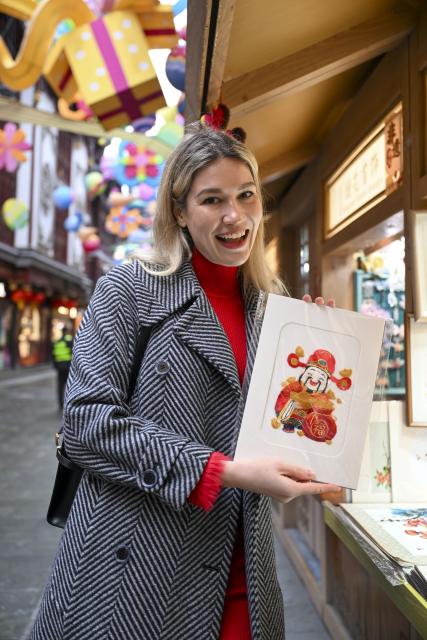 (260216) -- SHANGHAI, Feb. 16, 2026 (Xinhua) -- Aleksandra Antonenko poses for a photo with a Suzhou embroidery piece at a traditional crafts booth of Yuyuan Garden shopping mall in Shanghai, east China, Feb. 6, 2026.
  Aleksandra Antonenko moved from Russia to pursue her doctorate at Shanghai Jiao Tong University in 2022. She also began to show the charm of everyday life in China to the world with short video clips. 
  In the same year, she met Zhao Yiwei, now her husband, at a coffee shop. Zhao always encourages and supports her diligence, be it in academic pursue or in vlog production.
  With the Spring Festival around the corner, Aleksandra loves wandering through streets and picking out New Year goods. Back to her home, she adds her own tradition to the celebration by cooking Russian dishes for the holiday, turning the table into a blend of two cultures. 
  "The Spring Festival has deep cultural roots," Aleksandra said. "It's a time to bring family together and feel closer."
  Looking ahead, she plans to keep working toward her doctoral degree while continuing to document her life in China through videos. "Every day here brings something new," she said. "I'm excited to share real stories about China with the world."
  From a newbie international student to a Chinese daughter-in-law and a builder of cultural connections, Aleksandra's story reflects a simple belief: love knows no borders. (Xinhua/Chen Haoming)
