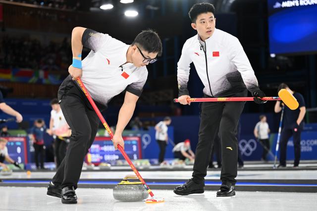 (260216) -- CORTINA D'AMPEZZO, Feb. 16, 2026 (Xinhua) -- Li Zhichao (L) and Fei Xueqing of China competes during the curling men's round robin session 8 match between China and Italy at the 2026 Milan-Cortina Winter Olympics in Cortina, Italy, Feb. 16, 2026. (Xinhua/Lian Yi)