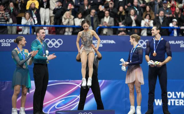 (260217) -- MILAN, Feb. 17, 2026 (Xinhua) -- Gold medalist Ryuichi Kihara of Japan lifts his partner Riku Miura to the podium to receive their medals as silver medalists Anastasiia Metelkina (1st L)/Luka Berulava (2nd L) of Georgia, and bronze medalists Minerva Fabienne Hase (2nd R)/Nikita Volodin (1st R) of Germany look on during the victory ceremony for Figure Skating Pair Skating at the Milan-Cortina 2026 Olympic Winter Games in Milan, Italy, Feb. 16, 2026. (Xinhua/Xue Yuge)