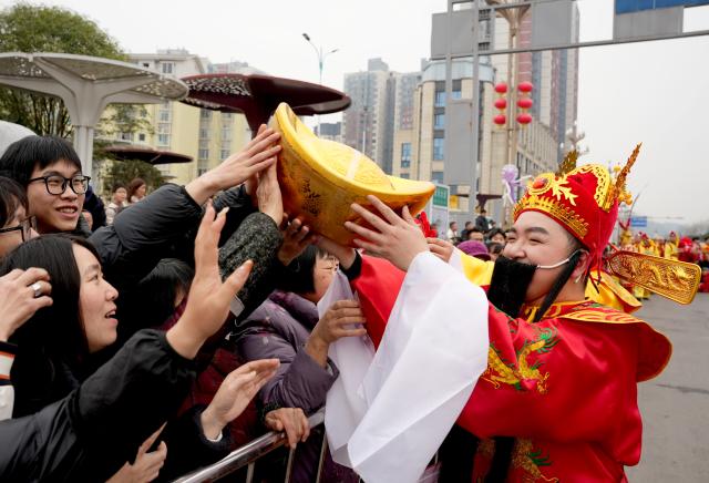 (260217) -- BEIJING, Feb. 17, 2026 (Xinhua) -- A man dressed as the God of Fortune interacts with visitors in Huaying City, southwest China's Sichuan Province, Feb. 17, 2026. This year's Spring Festival saw a surge of visitors eager to experience local cuisine, rich history and vibrant folk performances. (Photo by Zhou Songlin/Xinhua)