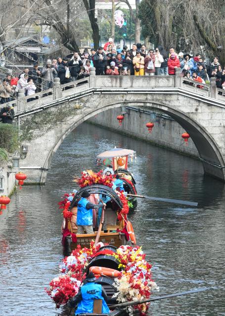 (260217) -- BEIJING, Feb. 17, 2026 (Xinhua) -- People watch a boat parade in Shaoxing, east China's Zhejiang Province, Feb. 17, 2026. This year's Spring Festival saw a surge of visitors eager to experience local cuisine, rich history and vibrant folk performances. (Xinhua/Weng Xinyang)