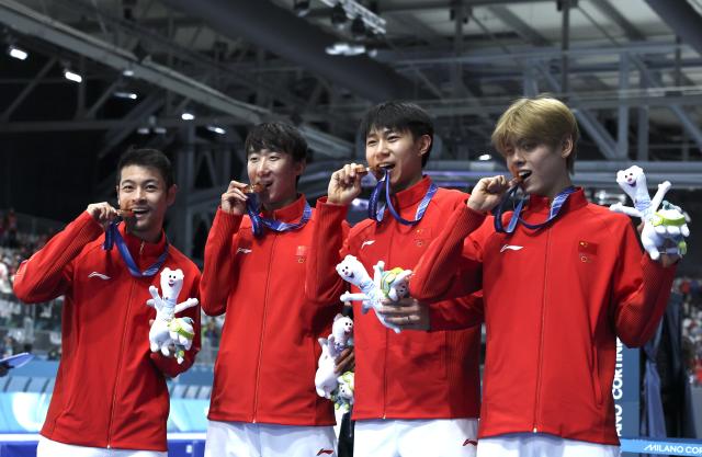 (260217) -- MILAN, Feb. 17, 2026 (Xinhua) -- Bronze medalists Liu Hanbin, Wu Yu, Li Wenhao and Ning Zhongyan of China bite their medals after the awarding ceremony of the speed skating men's team pursuit event at the Milan-Cortina 2026 Olympic Winter Games in Milan, Italy, Feb. 17, 2026. (Xinhua/Li Jing)