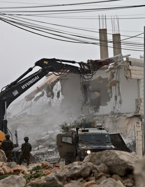 (260217) -- NABLUS, Feb. 17, 2026 (Xinhua) -- Members of Israeli forces stand guard as an Israeli excavator demolishes a house in Nablus in the northern West Bank, on Feb. 17, 2026. (Photo by Ayman Nobani/Xinhua)