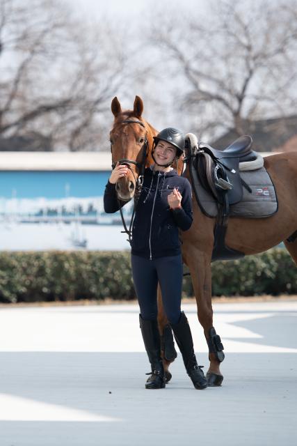 (260218) -- GUANGDE, Feb. 18, 2026 (Xinhua) -- Sasha poses for a photo with her horse Lector at the Yangtze River Delta International Equestrian Center in Dongting Town of Guangde City, east China's Anhui Province, Jan. 15, 2026. Sasha, an equestrian from Russia, once studied in Shanghai and later went to Europe to study equestrian sports, where she met coach Vasil and eventually married him. They have a lovely daughter named Maya. In 2023, Sasha's family moved to Guangde to start a new life, as her husband Vasil was invited to teach at the Yangtze River Delta International Equestrian Center.
  "Riding has always been my favorite," Sasha said in Chinese. Sasha's family now lives near the equestrian center, where she trains daily in equestrian show jumping, takes walks with her beloved horse, and sometimes helps with horse training. Looking ahead, she hopes to participate in more equestrian competitions and to one day own her own ranch.
  Beyond the racetrack, Sasha engages in cultural activities to learn about local customs and traditions. Her daughter Maya attends a local kindergarten and has learned Chinese. Her husband Vasil's equestrian teaching is well received by students. These experiences have helped Sasha feel a sense of belonging in a place once unfamiliar to her. "Guangde is picturesque and has friendly people. Living and training here makes me feel wonderful," said Sasha. (Xinhua/Zhang Duan)