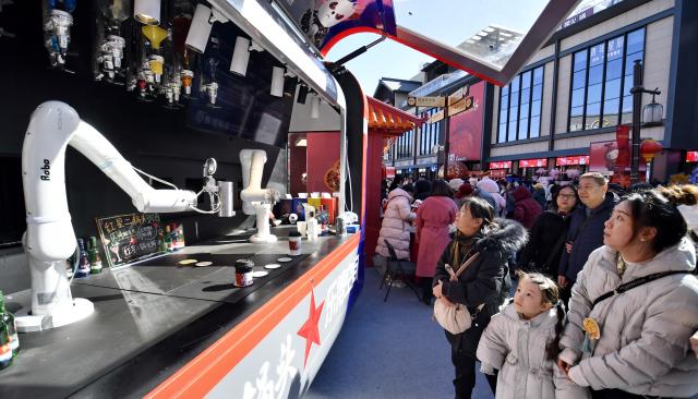 (260218) -- BEIJING, Feb. 18, 2026 (Xinhua) -- People look at a robot beverage bartender during a Spring Festival fair at Longfusi in Beijing, capital of China, Feb. 18, 2026. People visit cultural scenic areas in Beijing to feel the festive atmosphere of the Spring Festival. (Xinhua/Li Xin)