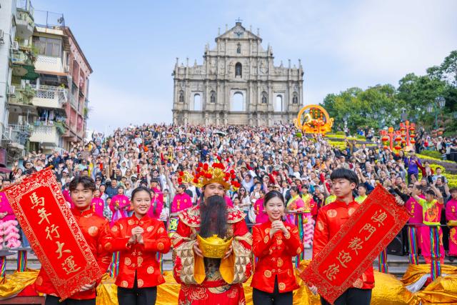 (260218) -- MACAO, Feb. 18, 2026 (Xinhua) -- A performer dressed as the "God of Wealth" (C) extends greetings to the crowd during a celebration of the Spring Festival in front of the Ruins of St. Paul's in south China's Macao, Feb. 18, 2026. (Xinhua/Cheong Kam Ka)